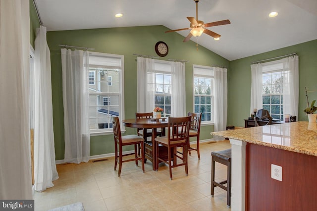 dining area featuring a healthy amount of sunlight, vaulted ceiling, baseboards, and light tile patterned flooring