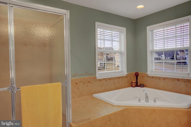 bathroom with a garden tub, plenty of natural light, and a shower stall