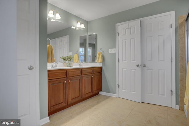 full bathroom featuring double vanity, baseboards, and a sink