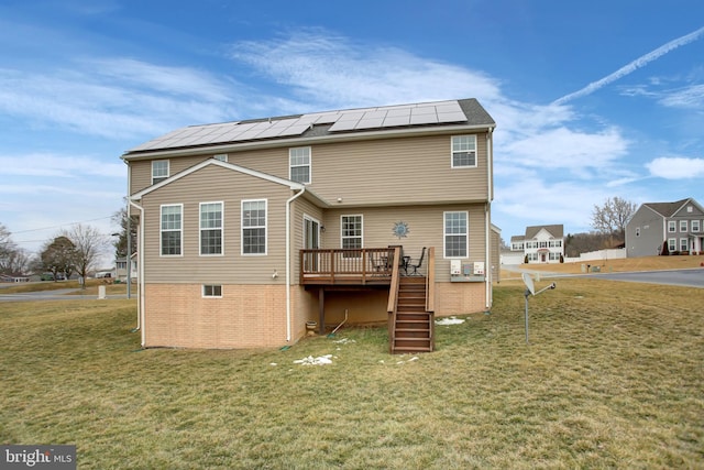 rear view of house featuring stairway, a deck, solar panels, and a yard