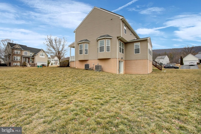 back of house with central AC unit, a lawn, and brick siding