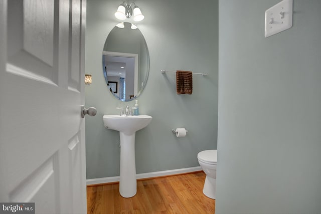 bathroom featuring a sink, toilet, baseboards, and wood finished floors