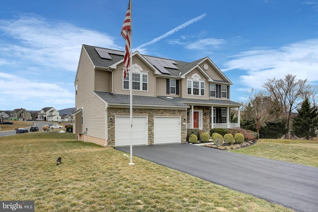 traditional-style house with aphalt driveway, an attached garage, stone siding, roof mounted solar panels, and a front lawn