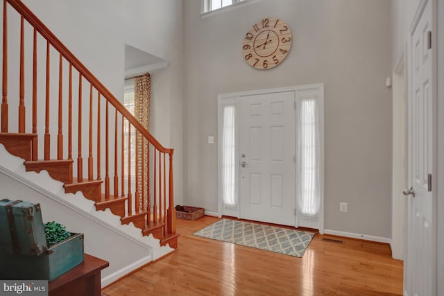 entryway featuring a high ceiling, wood finished floors, visible vents, and baseboards