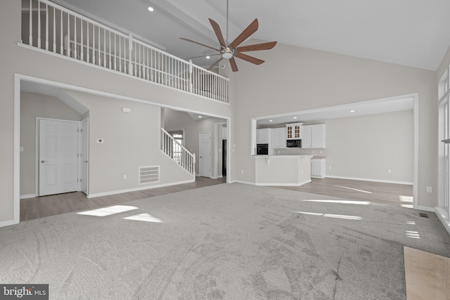 unfurnished living room featuring visible vents, baseboards, ceiling fan, carpet, and stairs