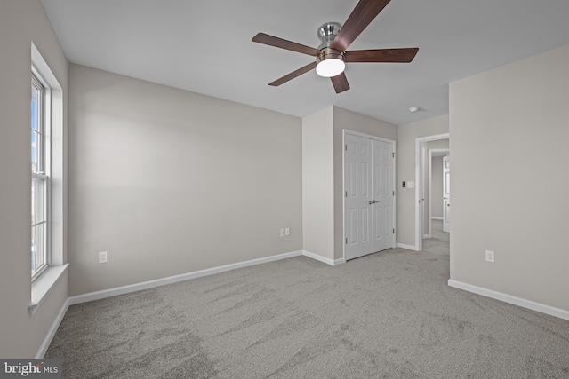 unfurnished bedroom featuring baseboards, a closet, a ceiling fan, and light colored carpet