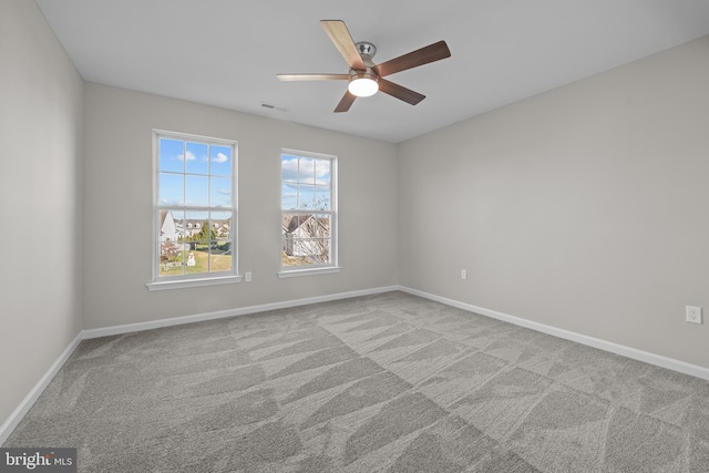 spare room with a ceiling fan, visible vents, light carpet, and baseboards