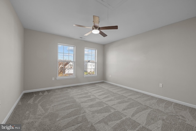 empty room with light carpet, attic access, baseboards, and ceiling fan