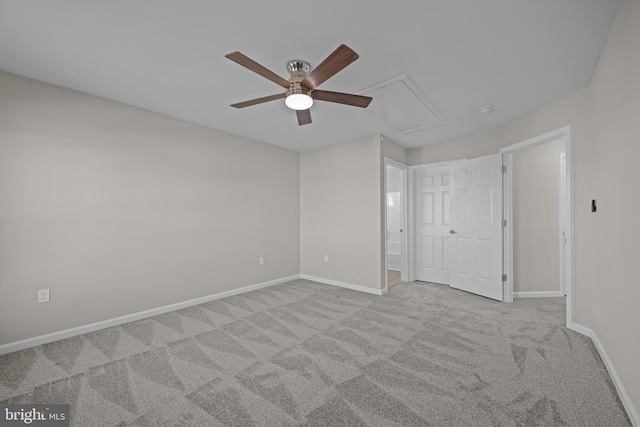 unfurnished bedroom with attic access, light colored carpet, baseboards, and a ceiling fan