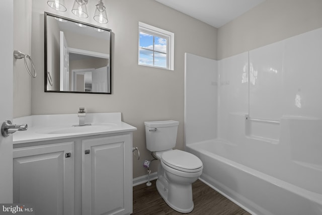 bathroom with baseboards, toilet, wood finished floors, vanity, and shower / bathing tub combination