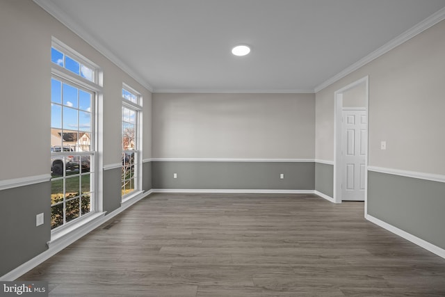 spare room with visible vents, crown molding, baseboards, and wood finished floors