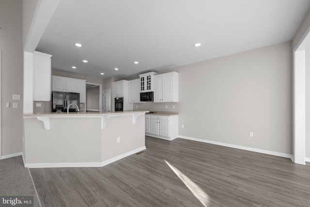 kitchen featuring white cabinets, a kitchen breakfast bar, a peninsula, black appliances, and recessed lighting