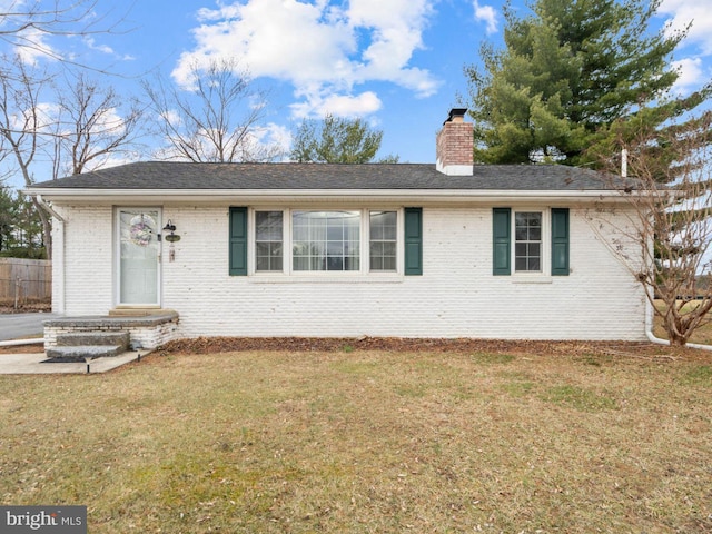 ranch-style house with brick siding, fence, roof with shingles, a chimney, and a front yard