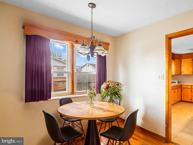 dining room with light wood-type flooring, baseboards, and a notable chandelier