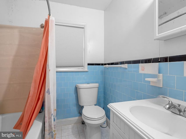 bathroom featuring tile walls, toilet, shower / bath combo with shower curtain, vanity, and tile patterned floors