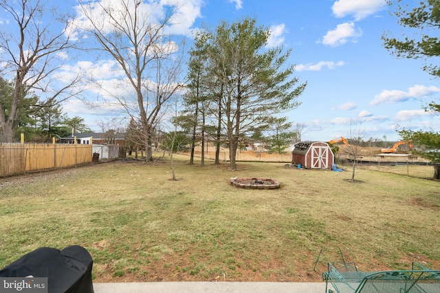 view of yard with a fire pit, a storage shed, an outdoor structure, and fence