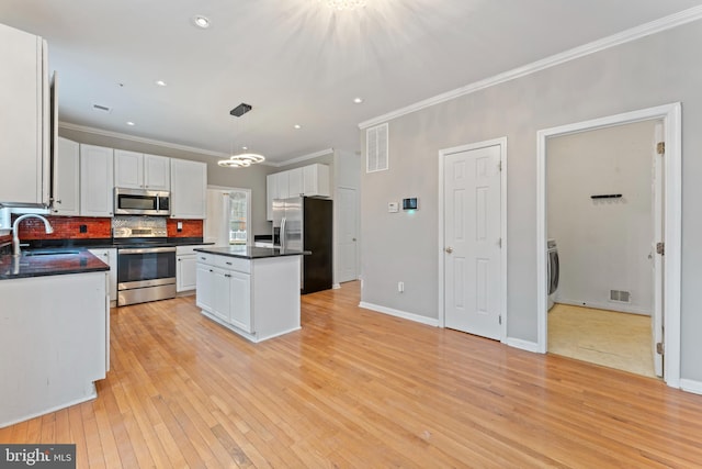 kitchen with dark countertops, white cabinets, appliances with stainless steel finishes, and a sink