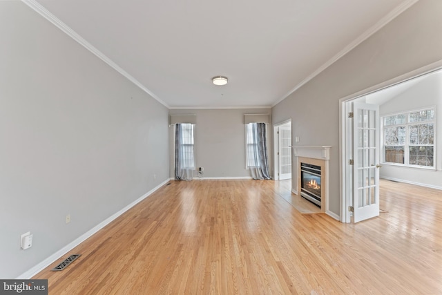 unfurnished living room with a fireplace with flush hearth, light wood-style floors, visible vents, and a wealth of natural light