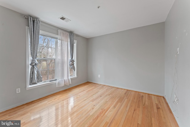 empty room featuring hardwood / wood-style flooring, plenty of natural light, baseboards, and visible vents