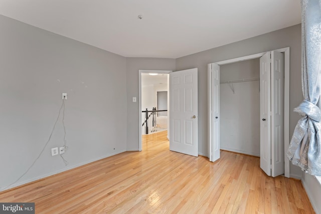 unfurnished bedroom with light wood-type flooring, baseboards, and a closet