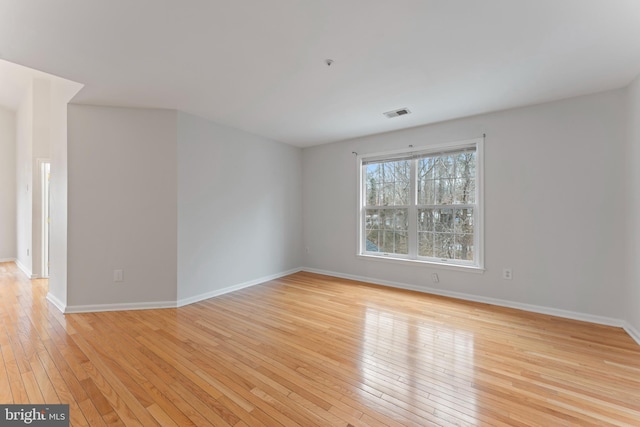 empty room featuring light wood finished floors, visible vents, and baseboards