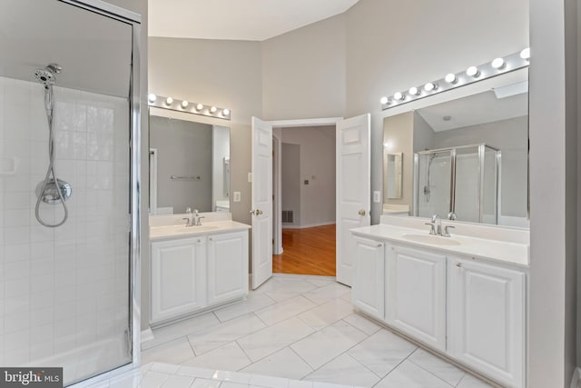 full bathroom with a sink, two vanities, a stall shower, and vaulted ceiling