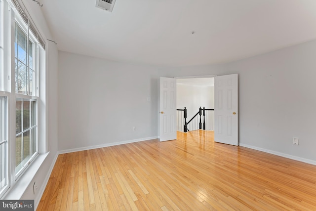 spare room with light wood-style flooring, baseboards, and visible vents