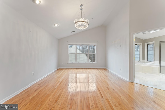 interior space featuring light wood finished floors, baseboards, an inviting chandelier, and vaulted ceiling