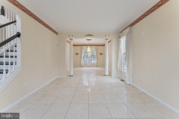 interior space featuring stairway, light tile patterned flooring, baseboards, and ornamental molding