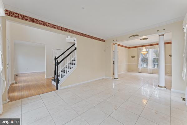 interior space featuring light tile patterned floors, stairway, baseboards, and ornamental molding