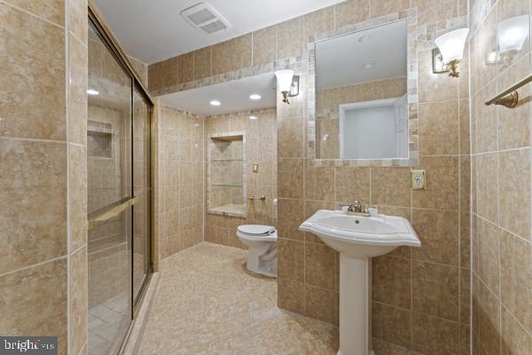 full bathroom featuring visible vents, tile patterned flooring, a shower stall, tile walls, and toilet