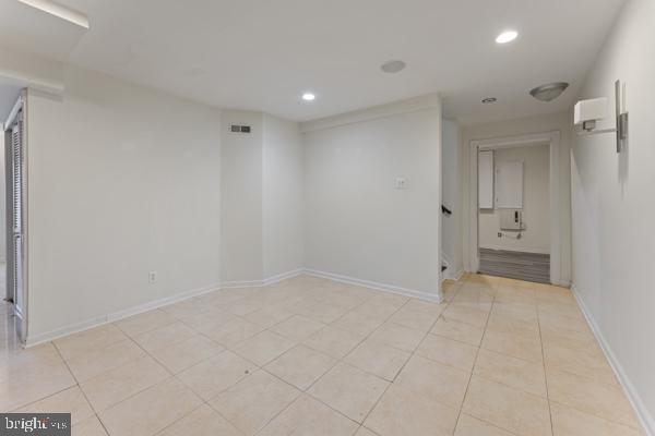 empty room featuring light tile patterned floors, baseboards, and recessed lighting