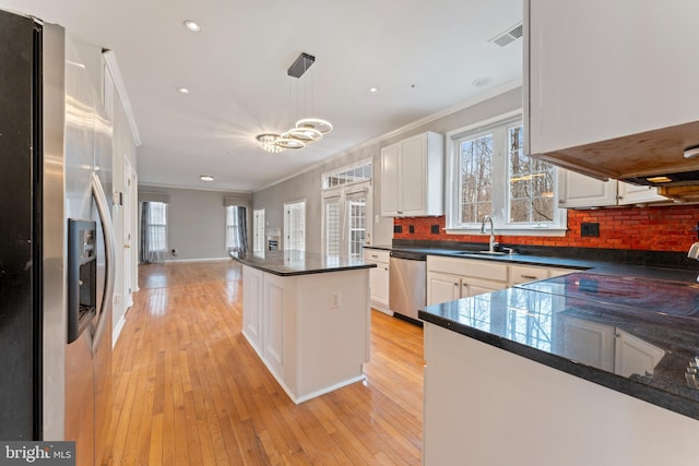 kitchen with dark countertops, tasteful backsplash, ornamental molding, appliances with stainless steel finishes, and a sink