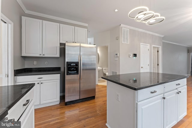 kitchen with white cabinets, stainless steel fridge with ice dispenser, light wood finished floors, and ornamental molding