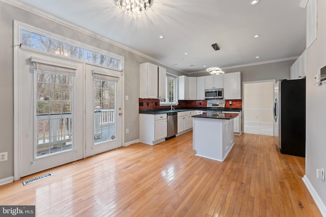 kitchen with visible vents, a sink, dark countertops, stainless steel appliances, and decorative backsplash