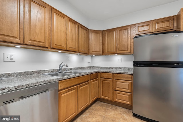 kitchen with appliances with stainless steel finishes, brown cabinetry, and a sink