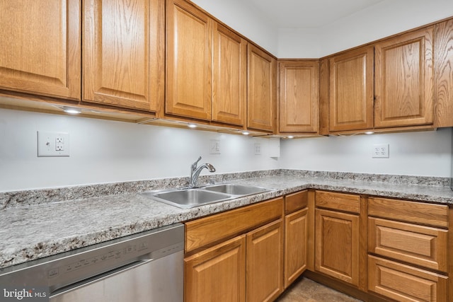 kitchen featuring brown cabinetry, light countertops, a sink, and stainless steel dishwasher