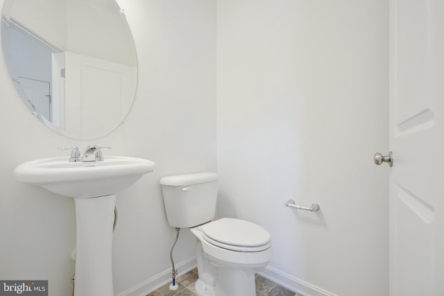 half bath with toilet, tile patterned flooring, and baseboards