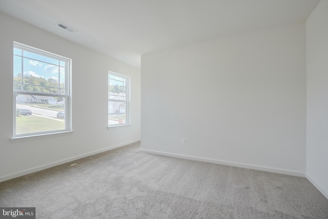 carpeted spare room featuring visible vents and baseboards