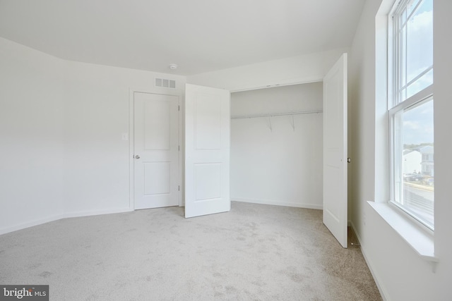 unfurnished bedroom featuring light carpet, baseboards, visible vents, and a closet