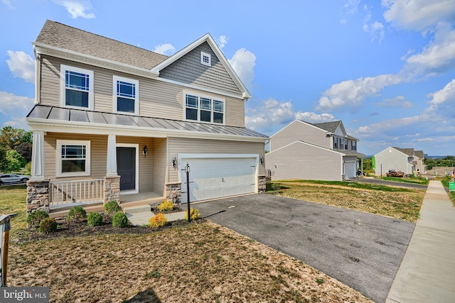 view of front of property featuring a garage, metal roof, aphalt driveway, covered porch, and a standing seam roof