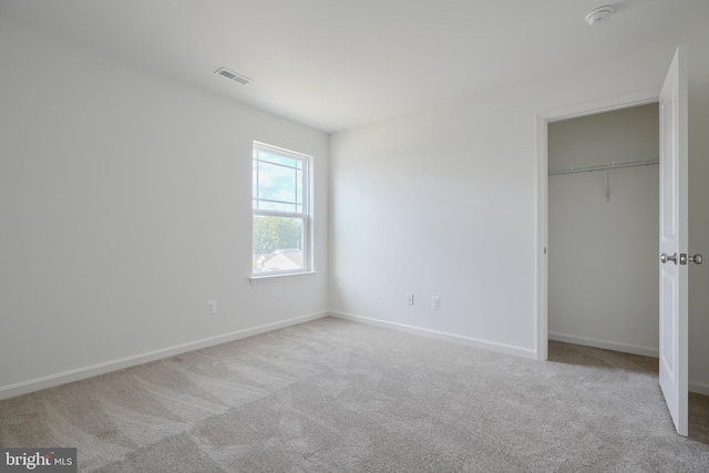 unfurnished bedroom featuring light colored carpet, a closet, visible vents, and baseboards