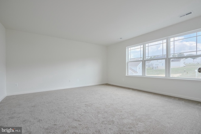 carpeted spare room with visible vents and baseboards