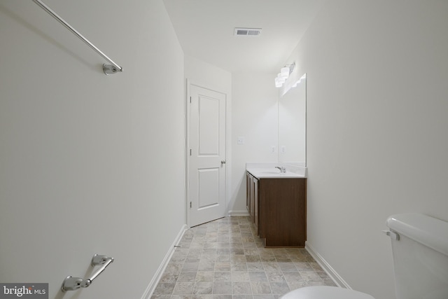 bathroom with toilet, visible vents, vanity, and baseboards