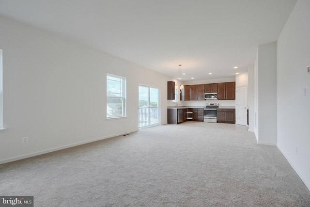 unfurnished living room with recessed lighting, light colored carpet, and baseboards