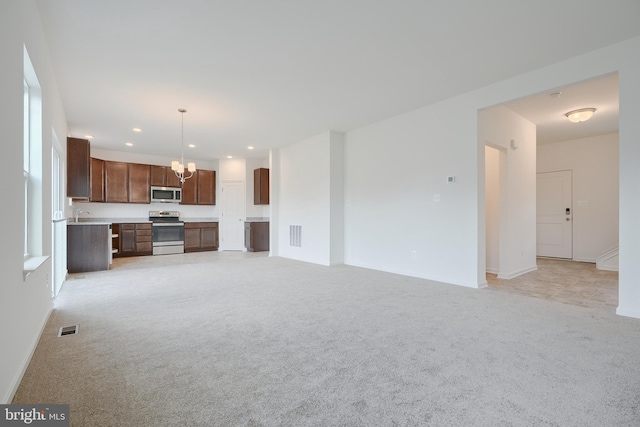 unfurnished living room with recessed lighting, light carpet, visible vents, and an inviting chandelier