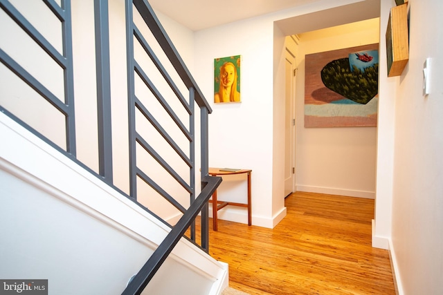 corridor featuring light wood-style floors, stairs, and baseboards