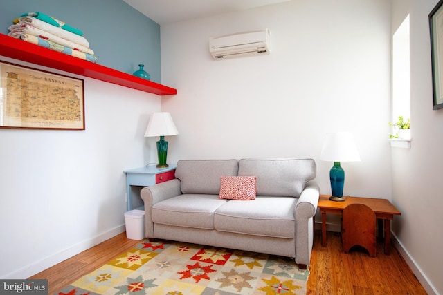 living room with a wall mounted air conditioner, wood finished floors, and baseboards