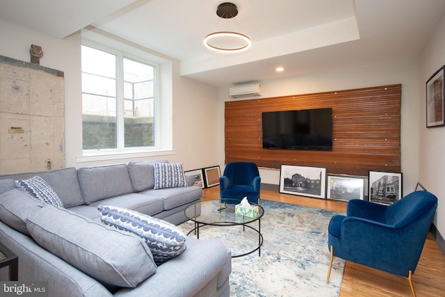 living area with an AC wall unit and wood finished floors