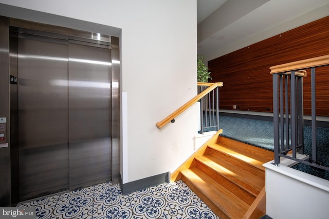 stairway featuring tile patterned flooring, elevator, and baseboards